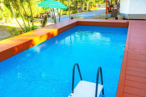 una gran piscina azul con sombrilla en Ingtarn Ressort At thasala en Ban Nai Thung