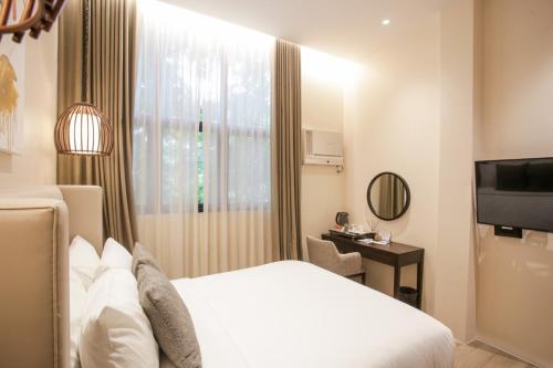 um quarto de hotel com uma cama e uma televisão em Girasol Tagaytay em Tagaytay