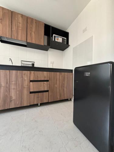 a kitchen with a black refrigerator and wooden cabinets at Departamento Estadio GNP antes foro sol, autodromo hermanos Rodríguez, palacio de los deportes, muy cerca de aeropuerto, CDMX in Mexico City