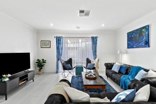 a living room with a couch and a tv at Coastal House Curlewis Getaway in Curlewis