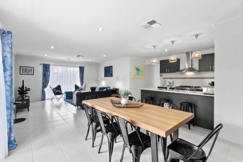 a kitchen and living room with a wooden table and chairs at Coastal House Curlewis Getaway in Curlewis