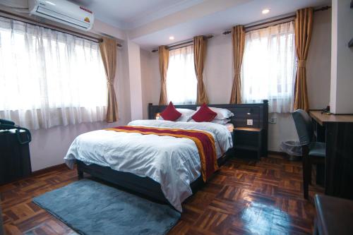 a bedroom with a bed and a desk and windows at Sandai Homes in Pātan