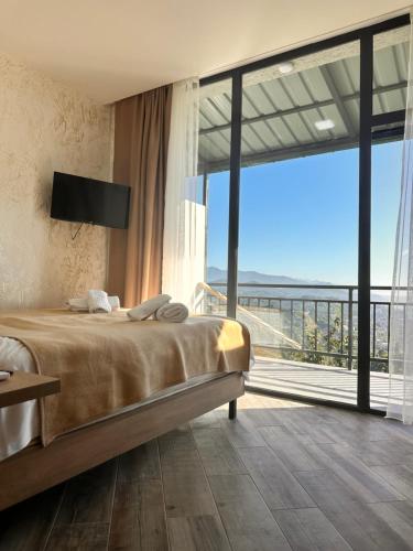 een slaapkamer met een bed en een groot raam bij Green Cape Tower in Batoemi