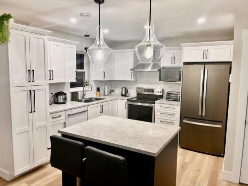 a kitchen with white cabinets and a black refrigerator at Modern Vac Home, private Hot tub, close to airport in Moncton