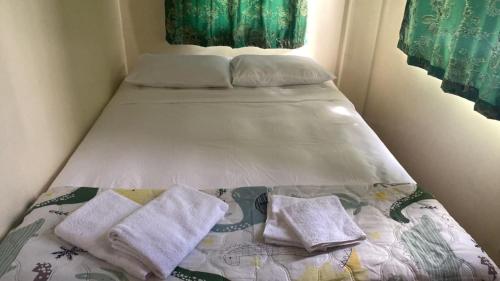 Una cama pequeña con dos toallas encima. en House Audry, en General Trias