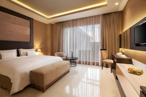 a hotel room with a bed and a television at Aveon Express Hotel by Daphna International in Yogyakarta