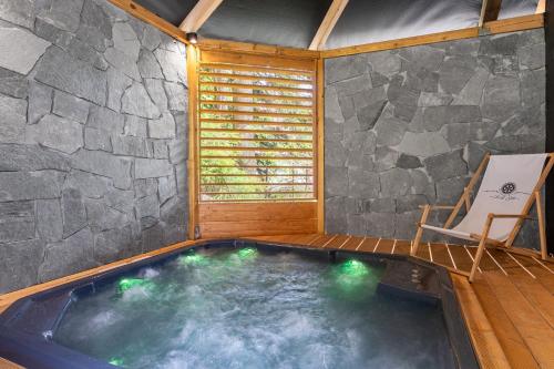 a hot tub in a room with a stone wall at Apartamenty - Król Gór - in Wisła