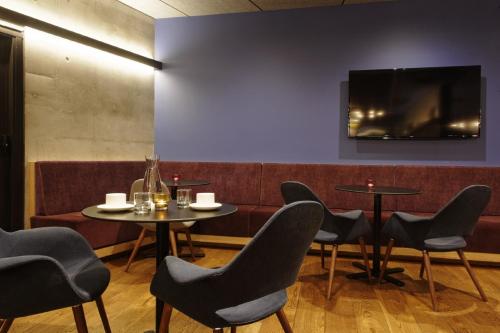 a restaurant with tables and chairs and a tv on the wall at Alpha Mosaic Hotel Fortitude Valley Brisbane in Brisbane