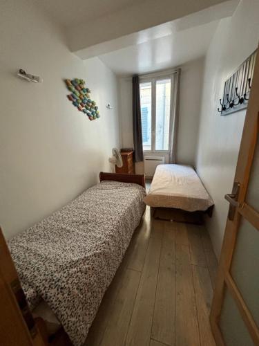 une petite chambre avec deux lits et une fenêtre dans l'établissement La Sardine au coeur du Panier, à Marseille