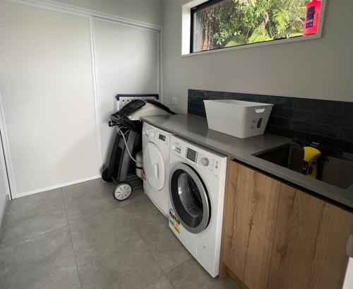 a kitchen with a washing machine and a sink at Kais Retreat in Punakaiki