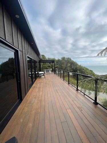 a wooden deck with a bench on the side of a building at Kais Retreat in Punakaiki
