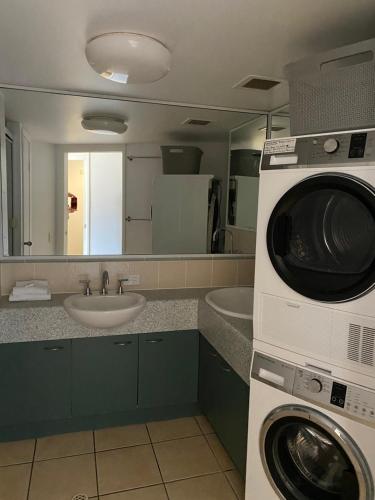 a bathroom with a washer and a sink and a washing machine at Kings Bay Apartments in Caloundra