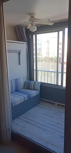 - un canapé bleu dans une chambre avec une grande fenêtre dans l'établissement studio Cap D'adge, au Cap d'Agde