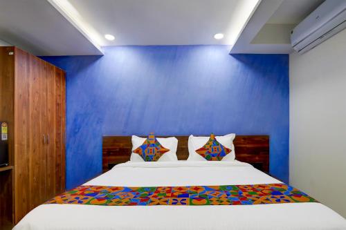 a bedroom with a bed with a blue wall at FabHotel Prime Srishoin in Hyderabad