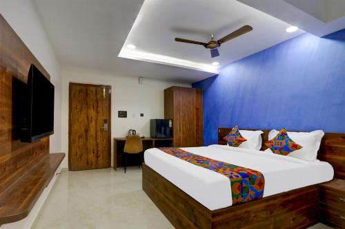a bedroom with a large bed with a blue wall at FabHotel Prime Srishoin in Hyderabad
