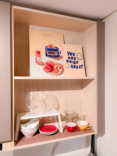 a cupboard filled with bowls and plates and a sign at Gold Coast PIK Apartments by Host Jess in Jakarta
