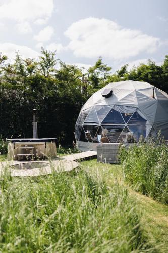 a dome tent in the middle of a field at Beautiful Olive Pod Geo Dome House with Hot Tub in East Horsley