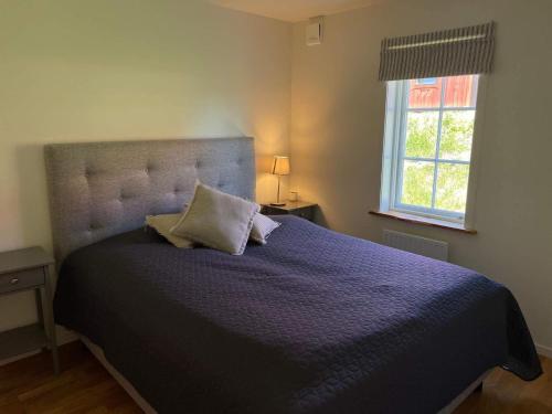 a bedroom with a large bed with a blue comforter and a window at 4 star holiday home in Sparreholm in Sparreholm