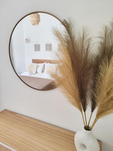 a mirror in a room with a bed and a vase with feathers at Noelia House Ammouliani in Ammouliani