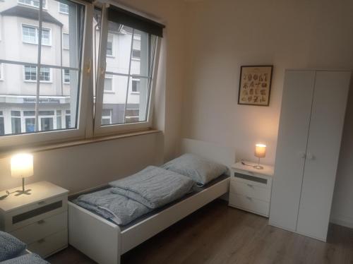 a small bedroom with a bed and two windows at Work and Stay Meinezhagen 5 schlafzimmer 10 betten, 2 badezimmer,150 qm in Meinerzhagen