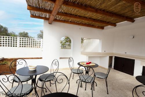 a patio with tables and chairs and a fireplace at Al Poggiale - Residenza Mediterranea in Porto Cesareo