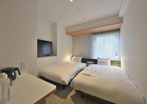 a hotel room with two beds and a tv at Prince Smart Inn Osaka Yodoyabashi in Osaka