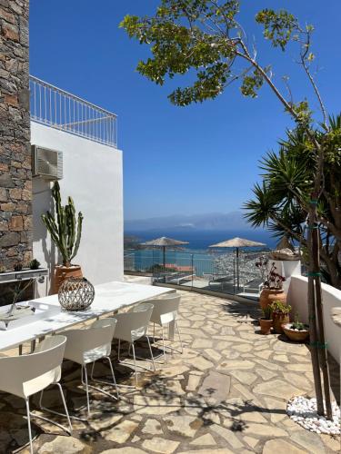 un patio con tavolo e sedie e l'oceano di Villa Romee with private swimmingpool and panoramic view on Elounda a Eloúnda