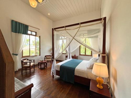 1 dormitorio con cama con dosel, mesa y sillas en PHA NYA RESIDENCE, en Luang Prabang