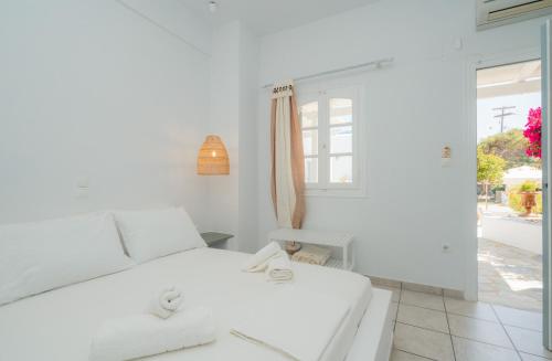 a white bedroom with a bed and a window at Nostos Sifnos in Apollonia