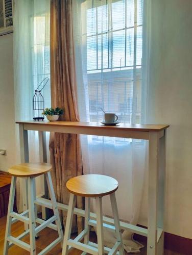 a table with two stools in front of a window at Sebastian's Place Bukidnon Unit1 Studio Type Near Dahilayan in Manolo Fortich