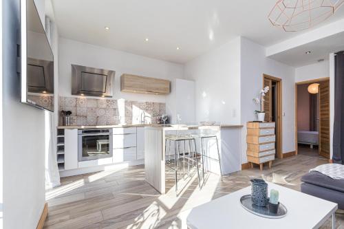 une cuisine et un salon avec des murs blancs et du parquet dans l'établissement 253 MONT BORON - Appartement 2p - Balcon plein sud - Climatisation, à Nice