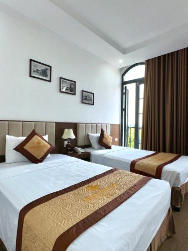 a hotel room with two beds and a window at VĨNH KHANG HẠ LONG HOTEL in Ha Long