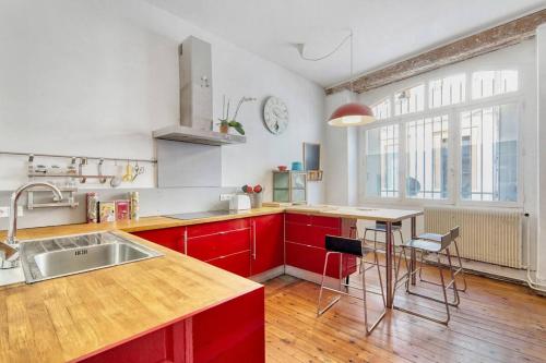 La cuisine est équipée de placards rouges, d'un évier et d'une table. dans l'établissement Rozane by Yumē, à Toulouse