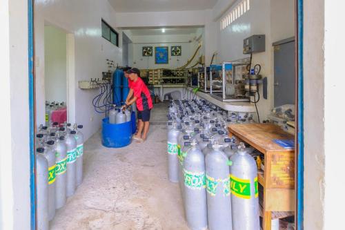 a man standing in a room with a bunch of water bottles at Malapascua Exotic Island Dive Resort in Daanbantayan