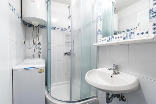 a white bathroom with a sink and a shower at Apartments Zoe in Bol
