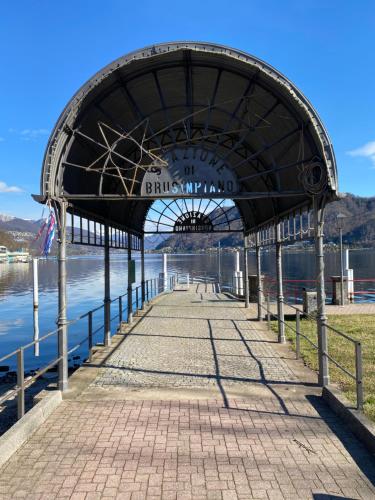 a pier with a building on the water at OSTERIA al CANTONACCIO ROOMS in Brusimpiano