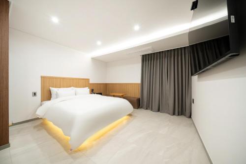 a bedroom with a white bed and a television at Hotel Urban Stay Ajung in Jeonju