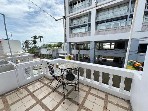 a balcony with a chair and a table and a building at Sea View Jomtien Guest House in Jomtien Beach