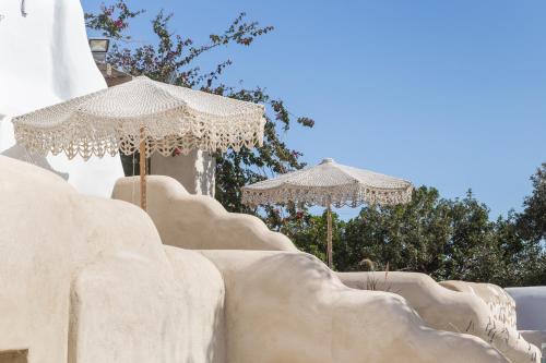 two umbrellas sitting on top of a stone wall at Kallos Villas & Suites in Naxos Chora