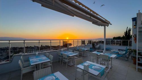 a patio with tables and chairs on a balcony with the sunset at La Bella Suit Otel in Kusadası