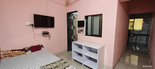 a pink room with a bed and a tv at Kulswami Cottage Alibaug in Alibaug