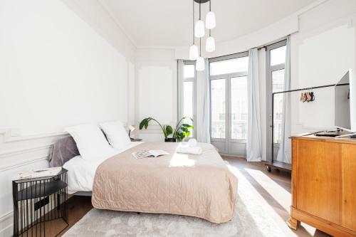 une chambre blanche avec un lit et une télévision dans l'établissement Vacances Au Palace - Happy Rentals, à Menton