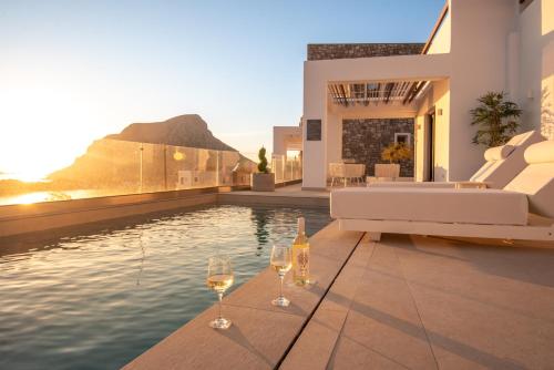 two glasses of wine sitting on the edge of a swimming pool at Mia Anasa - Luxury Suites in Masouri