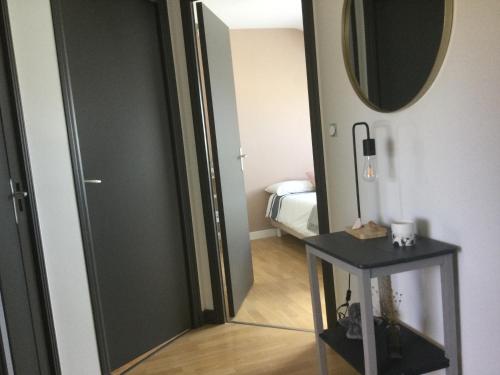 Cette chambre comprend un miroir, une table et un lit. dans l'établissement Maison dans un écrin de verdure, à Saint-Brieuc