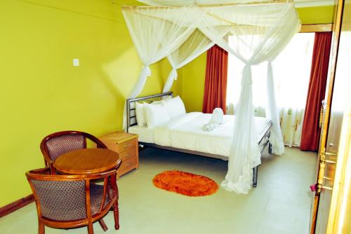 a bedroom with a bed and a table and chair at Wagon Wheel Hotel Eldoret in Eldoret