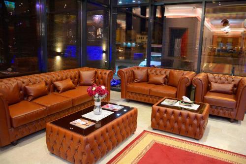 a living room with brown leather couches and a table at فندق فيفتى ايت السالمية in Kuwait