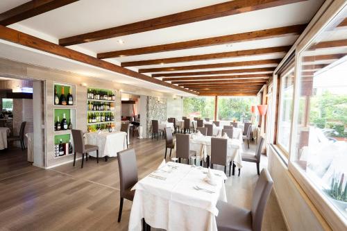 a restaurant with white tables and chairs and windows at Hotel Ristorante Le Rose in Briatico