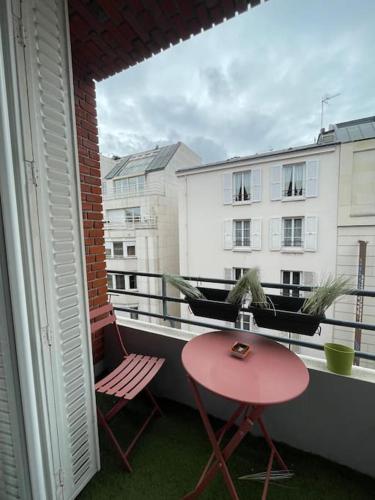 d'un balcon avec une table et des chaises rouges ainsi qu'une fenêtre. dans l'établissement Bienvenue chez Julie, à Levallois-Perret