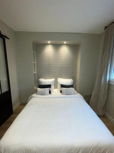 - un grand lit blanc avec des oreillers dans une chambre dans l'établissement Bienvenue chez Julie, à Levallois-Perret