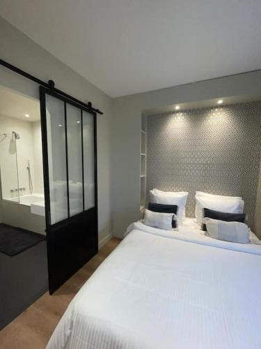 une chambre avec un grand lit blanc et une salle de bain dans l'établissement Bienvenue chez Julie, à Levallois-Perret